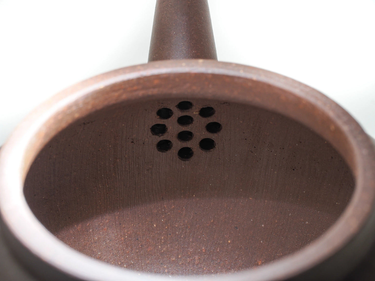 Close-up of the internal filter holes inside the Bronze Grade teapot, showing the porous clay structure.