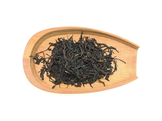 Tight, elegant dry leaves of Yixing Gong Hong black tea on a bamboo tray